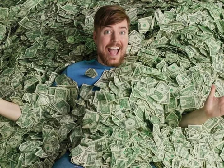 MrBeast lying in a pile of dollar bills